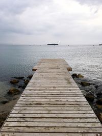 Wooden pier over sea against sky