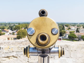 Close-up of coin-operated binoculars against buildings in city