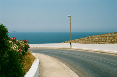 Road by sea against clear sky