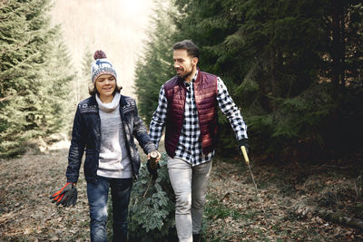 Happy father and son walking with branch in forest