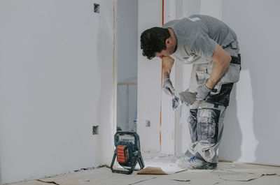 A young builder is plastering a doorway.