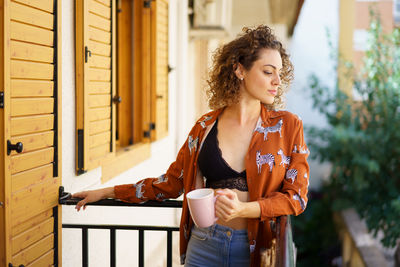 Portrait of young woman standing against wall