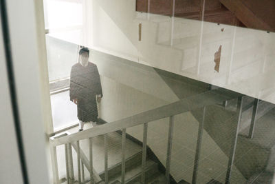 Portrait of man in graduation gown standing on stairs in building
