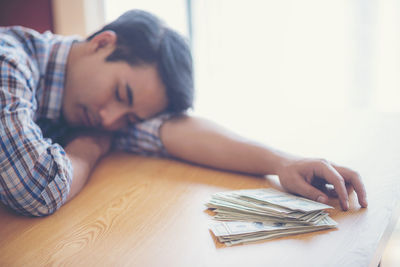 Close-up portrait of young woman lying on table at home