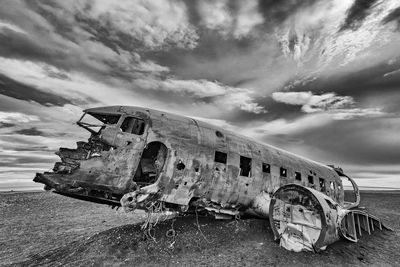 Abandoned airplane at beach against sky