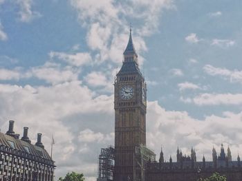 Low angle view of clock tower against cloudy sky