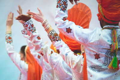Rear view of people in traditional clothing with arms raised