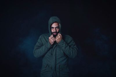 Man wearing winter jacket against black background