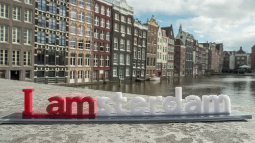 Information sign by river against buildings in city