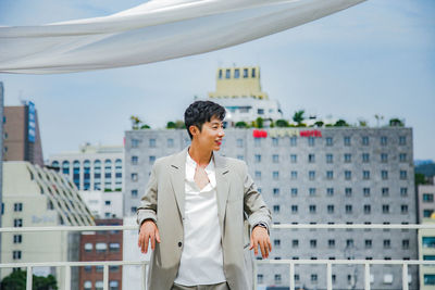 Smiling young man standing by railing in city