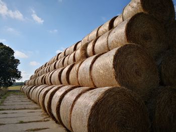 Stack of hay bales on field against sky