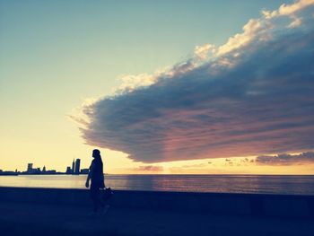 Silhouette man on beach against sky during sunset