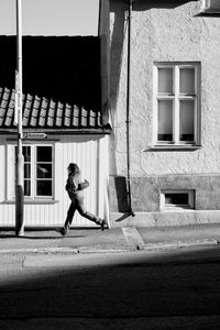 Side view of woman walking against building