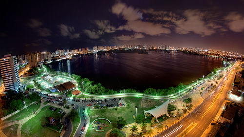 High angle view of illuminated city by sea against sky