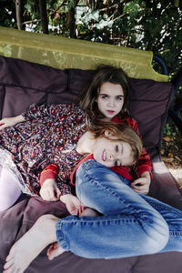Portrait of mother and girl sitting on bench