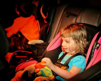 Girl looking away while sitting on baby seat in car