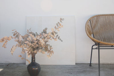 Close-up of vase on table against wall at home