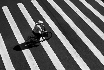 High angle view of man riding bicycle on zebra crossing
