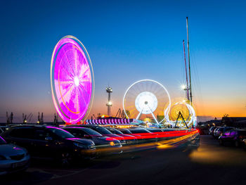 Illuminated ferris wheel against sky in city