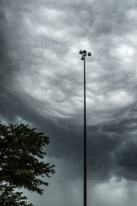 Low angle view of floodlight against cloudy sky