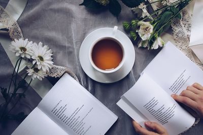 High angle view of hand holding coffee cup on table