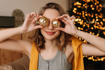 A pretty girl in pajamas rejoices and smiles during the christmas holidays in cozy bedroom interior