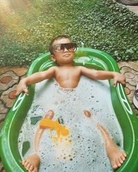 High angle view of shirtless boy relaxing in bathtub outdoors