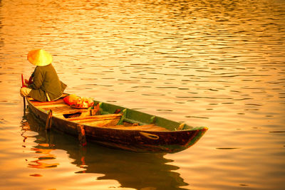 Person sitting on moored boat in lake