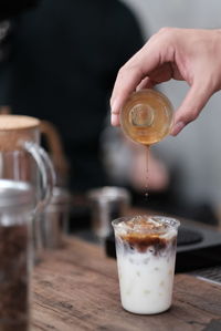 Midsection of person pouring drink in glass on table