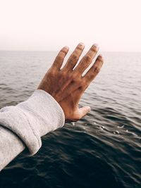 Cropped hand of man against sea