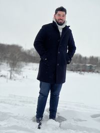 Portrait of young man standing on snow covered field