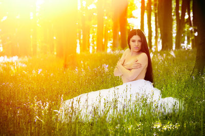 Portrait of young woman standing by plants in forest