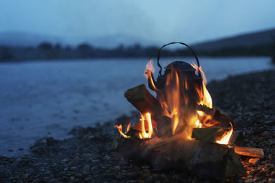 Metal kettle in campfire at dusk