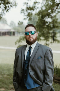 Portrait of young man standing against trees