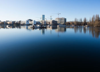 Reflection of buildings in lake against clear sky