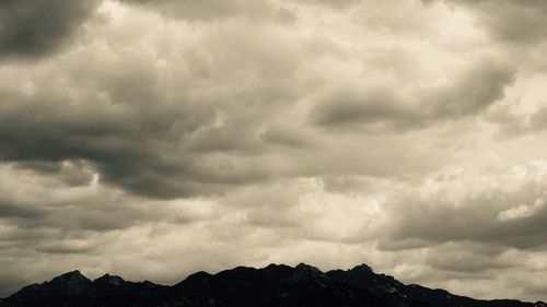 Low angle view of storm clouds over silhouette landscape