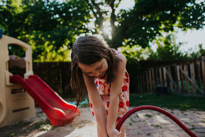 Young girl playing in backyard with garden hose