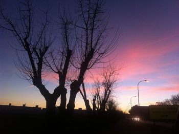 Silhouette of bare trees against sky at sunset