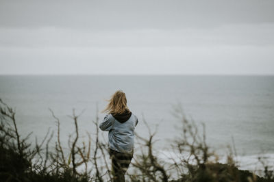 Rear view of woman looking at sea against sky