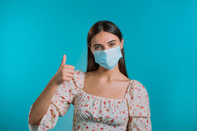 Portrait of young woman against blue background