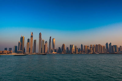 River by modern buildings against clear sky during sunset