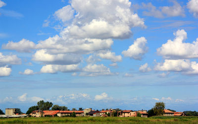 Houses on field against cloudy sky