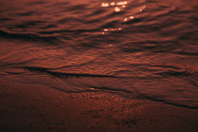 Water on shore at beach during sunset