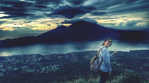 Portrait of young woman standing on mountain against sky