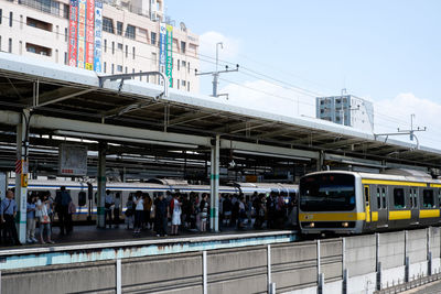 Train at railroad station in city against sky