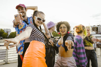 Portrait of happy non-binary friends having fun while dancing on promenade