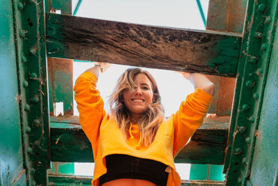 Portrait of smiling young woman standing against railway bridge