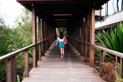 Woman walking on footbridge amidst trees