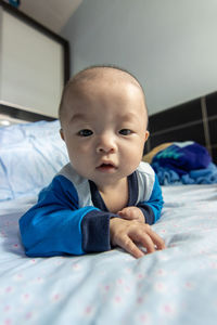 Portrait of cute baby boy on bed at home