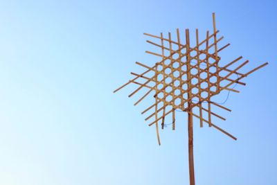 Low angle view of parasol against clear blue sky